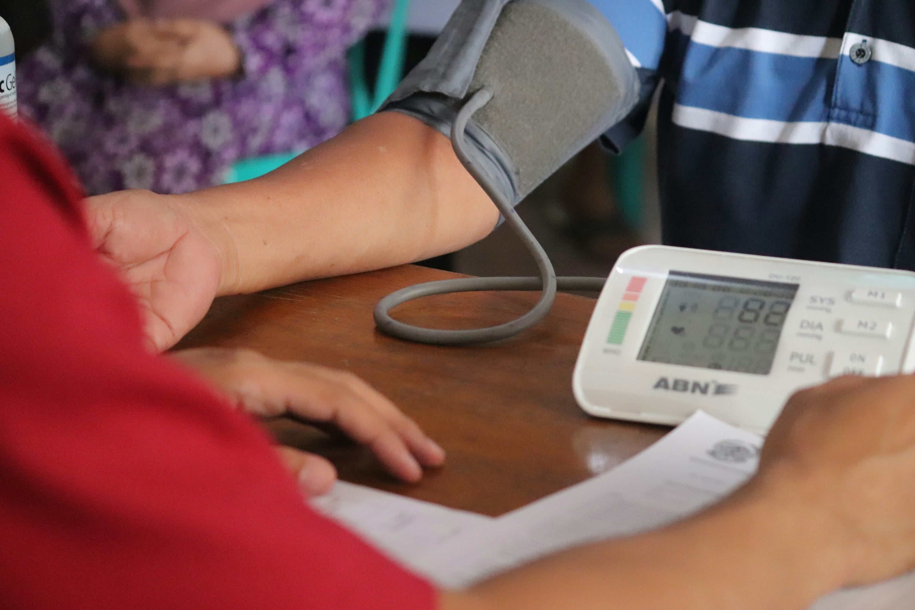 Tensiómetro digital midiendo la tensión en el brazo de un paciente, con el registro al lado