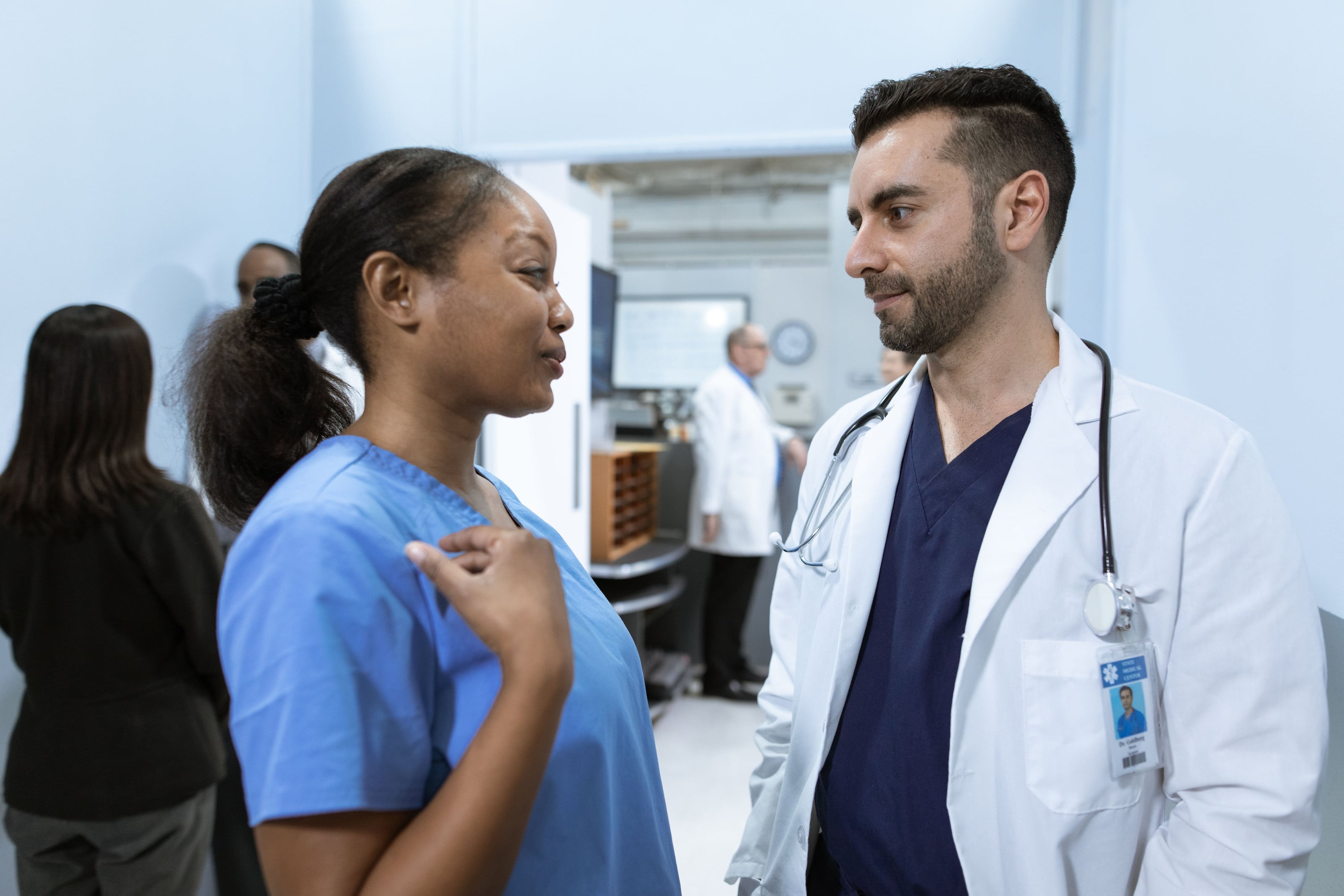 Médico y enfermera conversando en el pasillo de la clínica