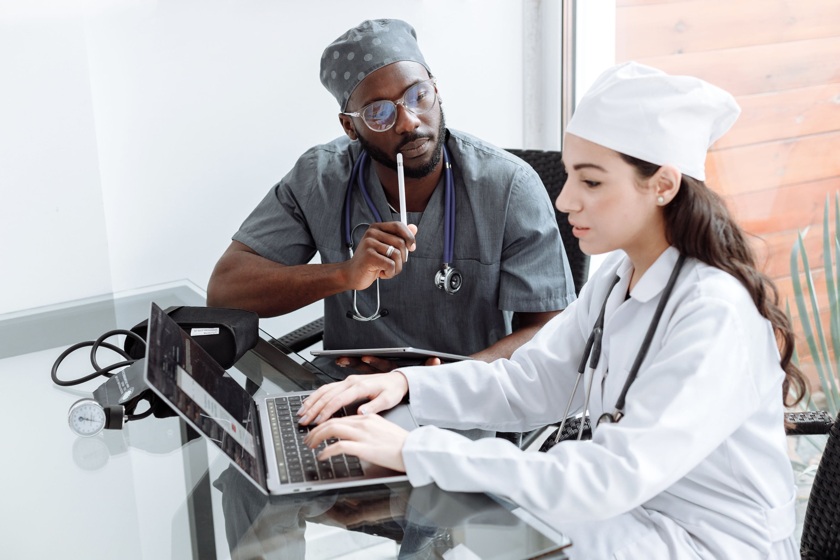 Un médico y una médica revisando juntos un caso en el portátil